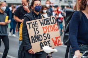 3x2Climate change is stressing us out 1 Climate change activist holding a banner with the message "The world is dying and so are we"