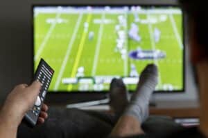 3x2participatinginsportsbyremotecontrol A man watches football on television.