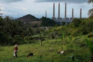 3x2Can Indonesia bid farewell to coal A woman leads her goats as Suralaya coal power plant looms in the background in Cilegon, Indonesia.
