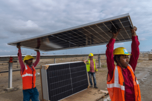 India's Energy Transition 900x600 Workers carry a solar panel for installation