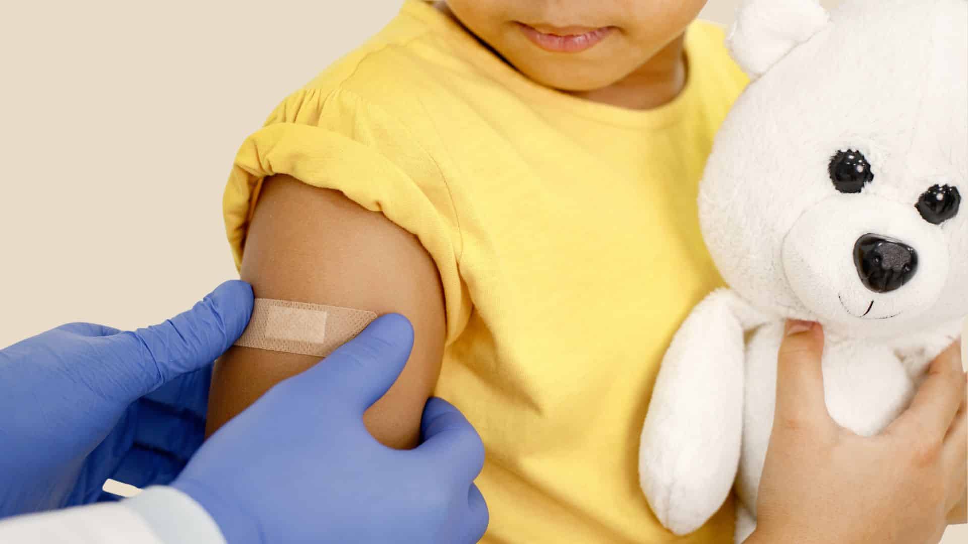 A medical worker sticks a band-aid on the arm of a child 