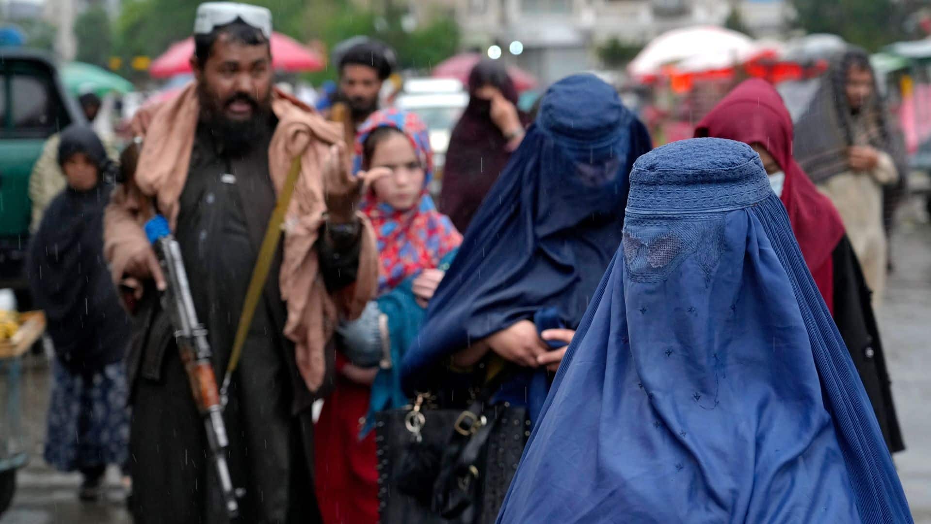 Should discrimination of women Afghan women walk through the old market as a Taliban fighter stands guard, in downtown Kabul, Afghanistan.