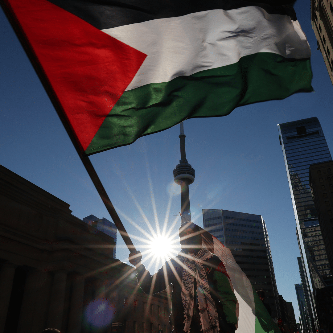 Ceasefire now protest (1) A protestor holding up a Palestinian flag in Toronto, Canada i
