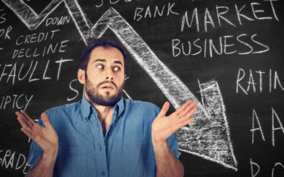 A man shrugs in confusion against a blackboard covered with economic terms.