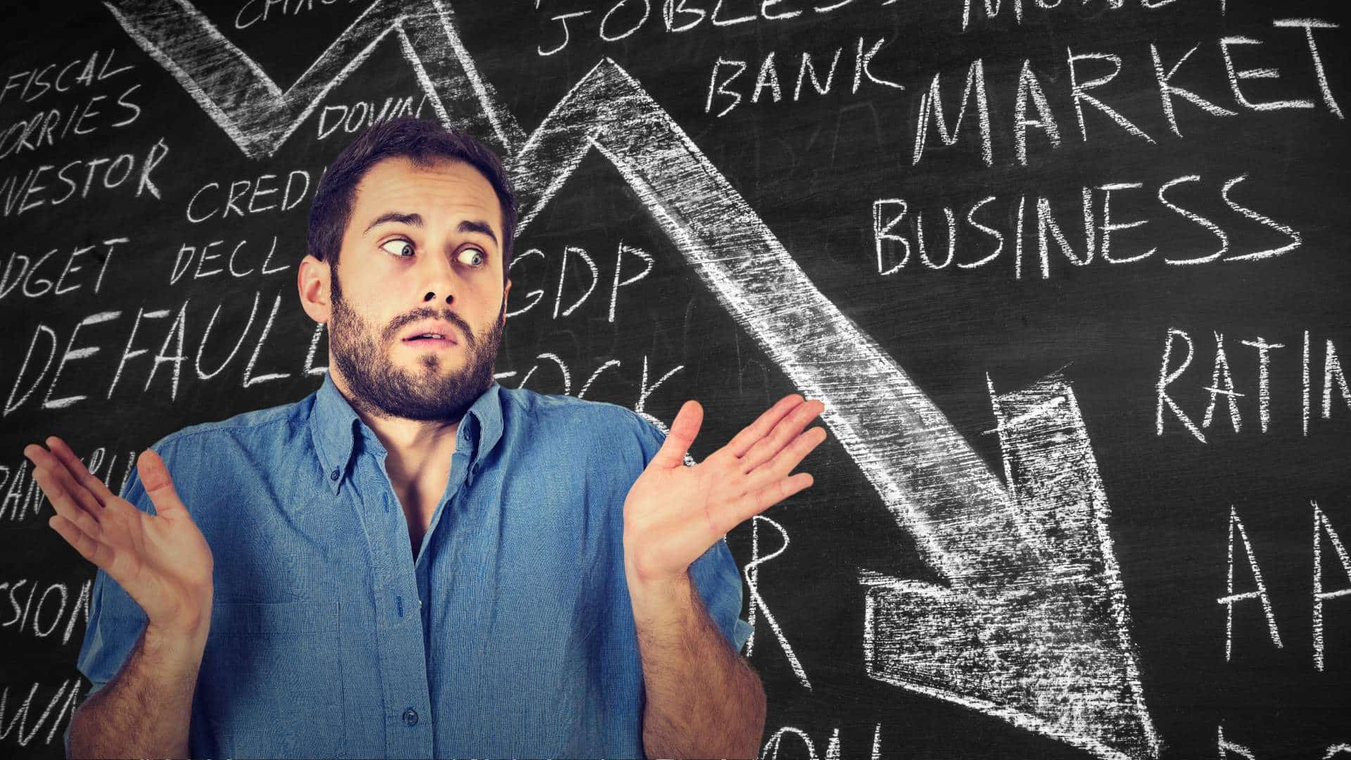 A man shrugs in confusion against a blackboard covered with economic terms.