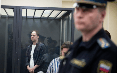 Wall Street Journal reporter Evan Gershkovich, left, stands in a glass cage in a courtroom at the First Appeals Court of General Jurisdiction in Moscow