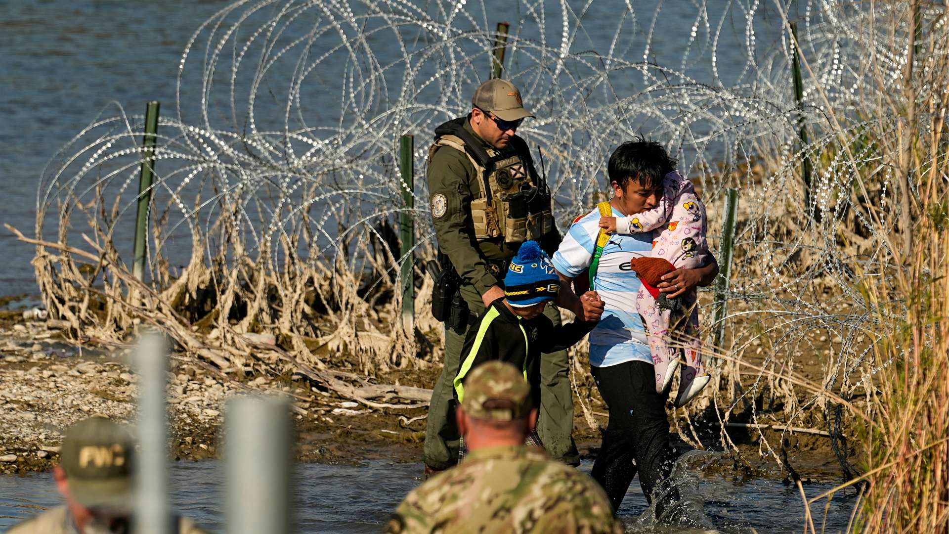 Mexican border A man carries a child as they are taken into custody by officials at the Texas-Mexico border