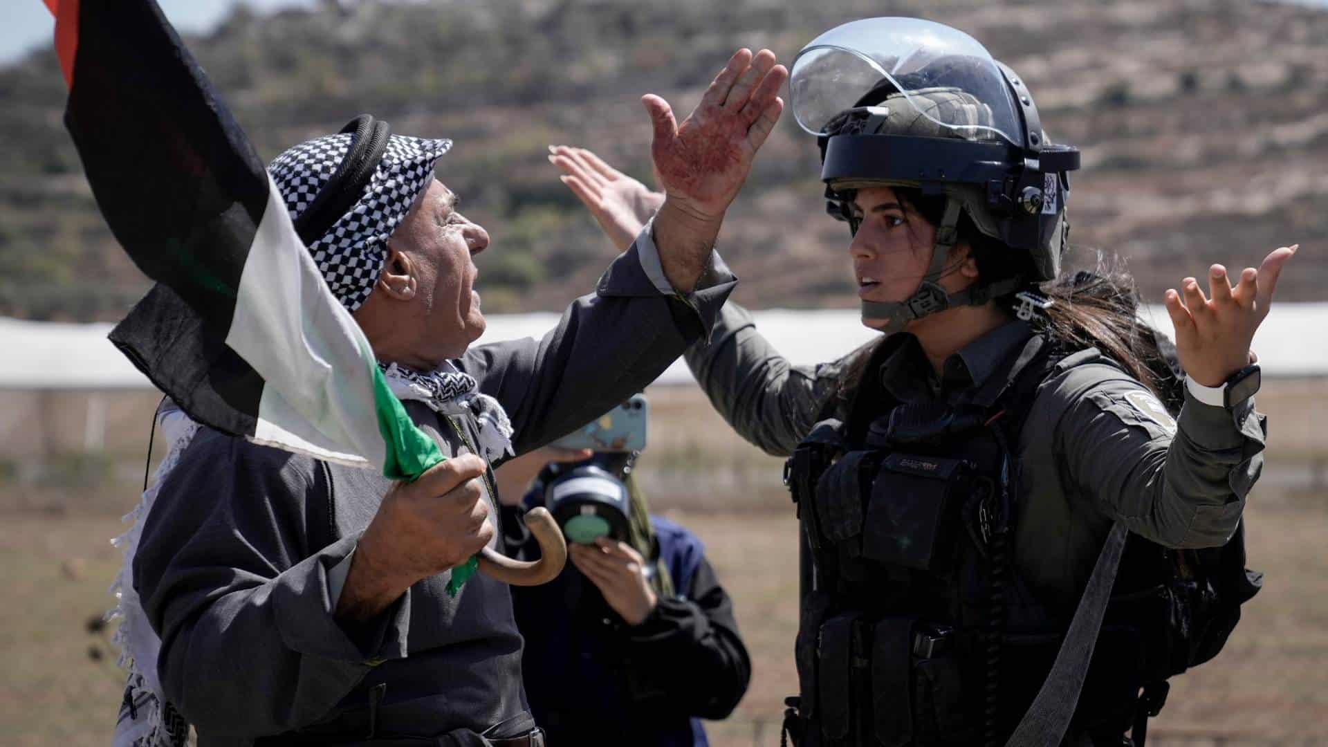 Untitled design (4) A Palestinian protester argues with Israeli security forces to prevent shooting tear gas at Palestinian protesters during a demonstration against Israeli settlements in the West Bank.