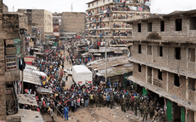 Excavators bring down homes as people watch.