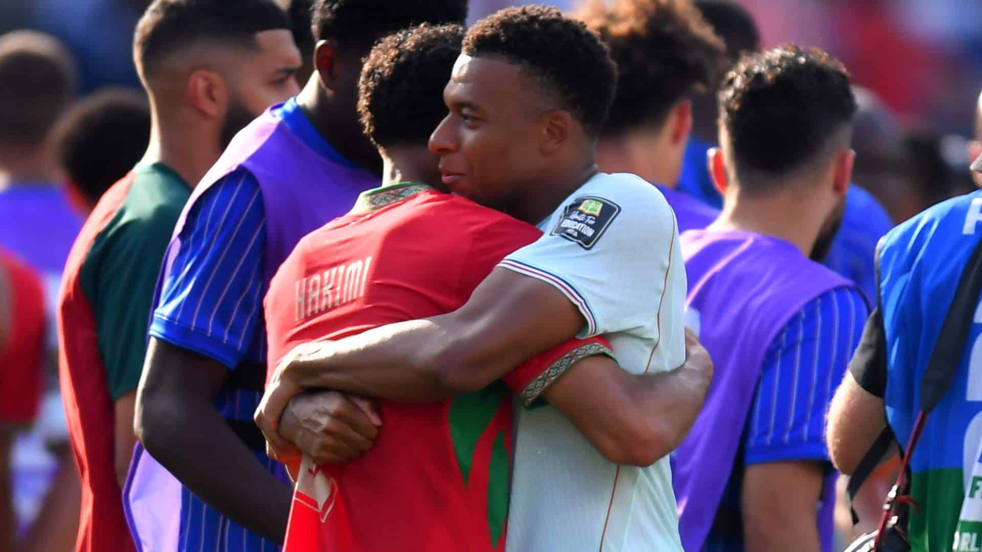 Opposing team members Achraf Hakimi and Kylian Mbappe hug after a World Cup game. 