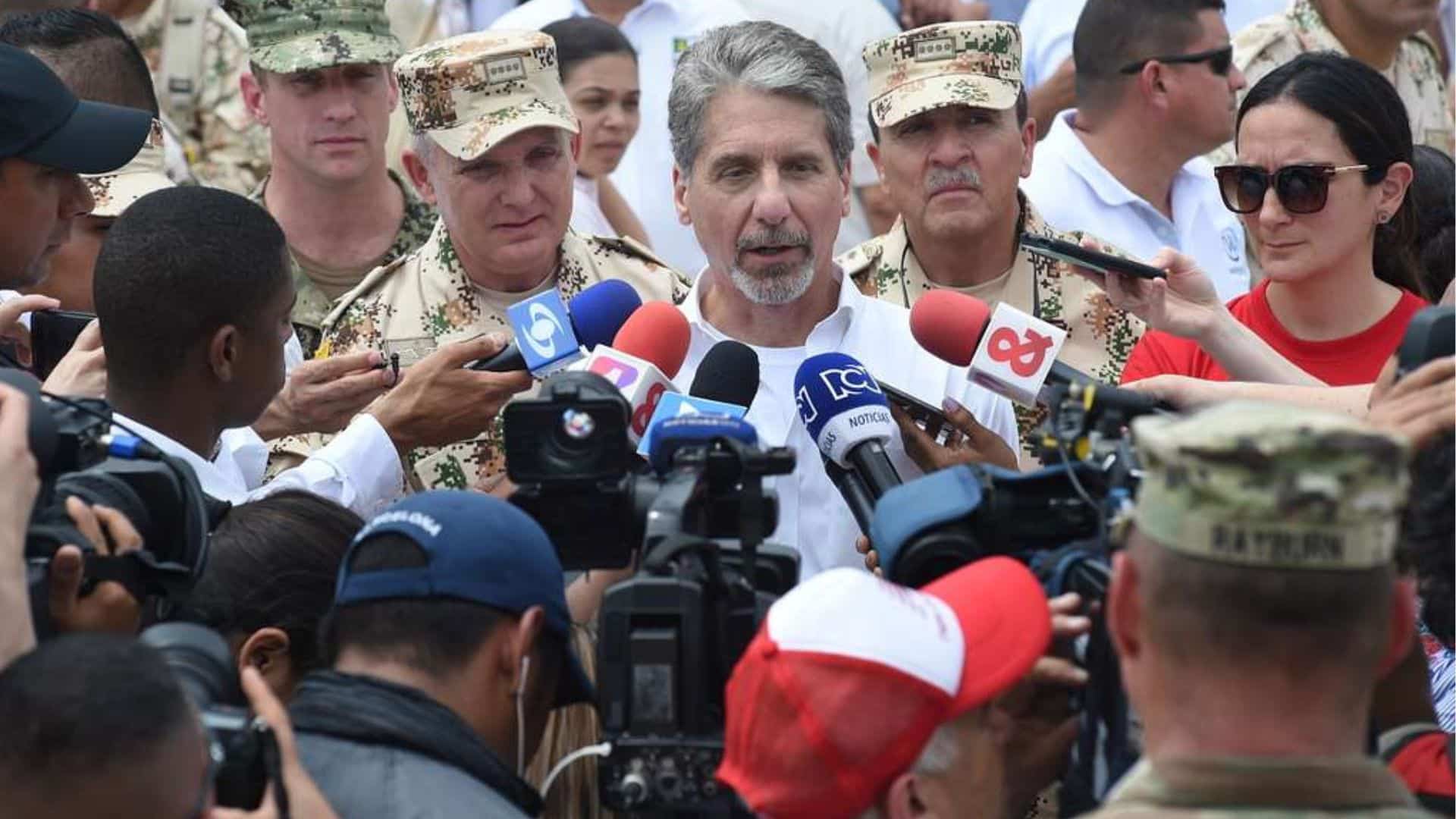 Reporters with microphones surround an official